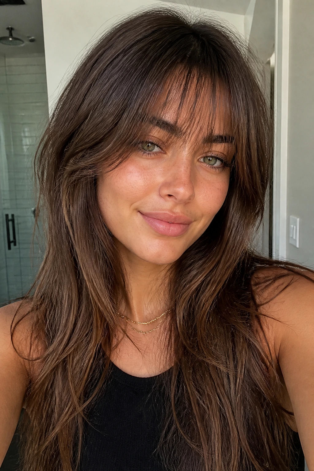 Close-up of a real person with tapered bangs and air-dry layers in a bright interior