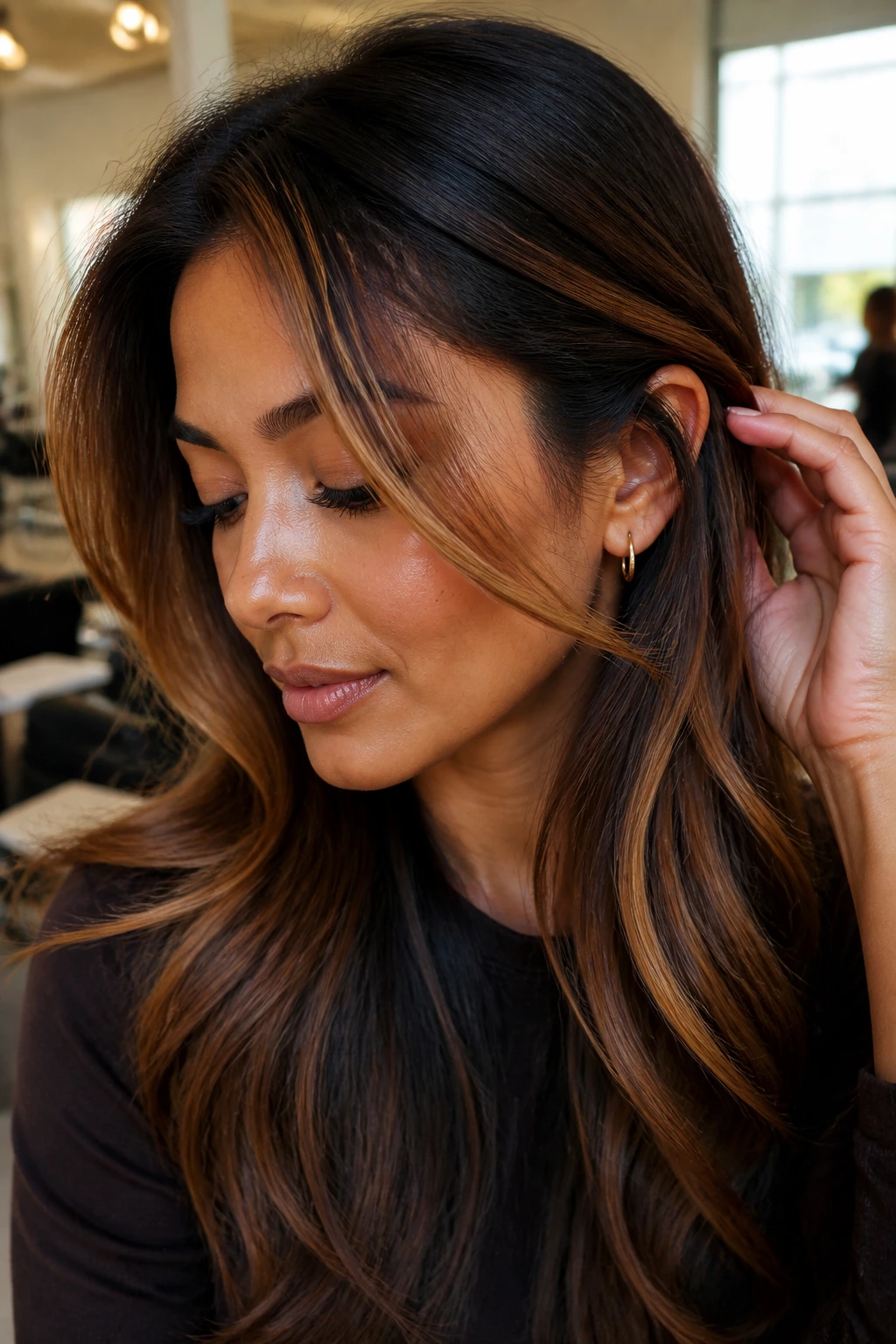 Close-up portrait of a real woman with amber front ribbons in dark hair, warm window light.