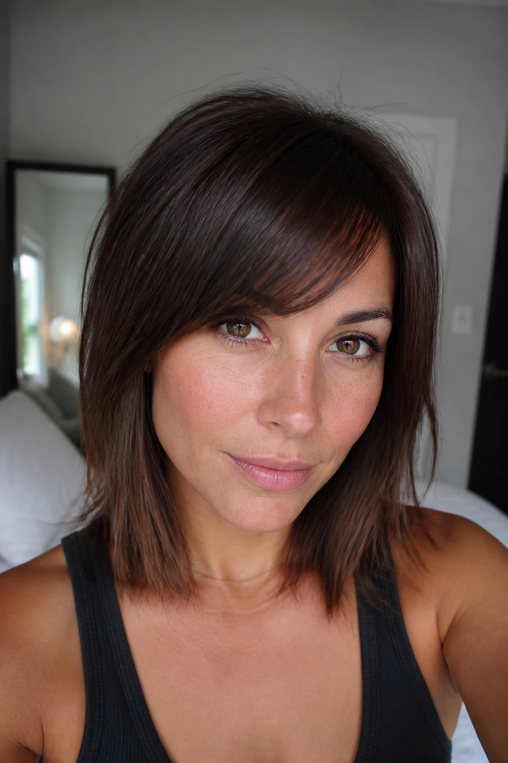 Close-up portrait of a real woman with angled bangs framing the cheekbones in warm natural light