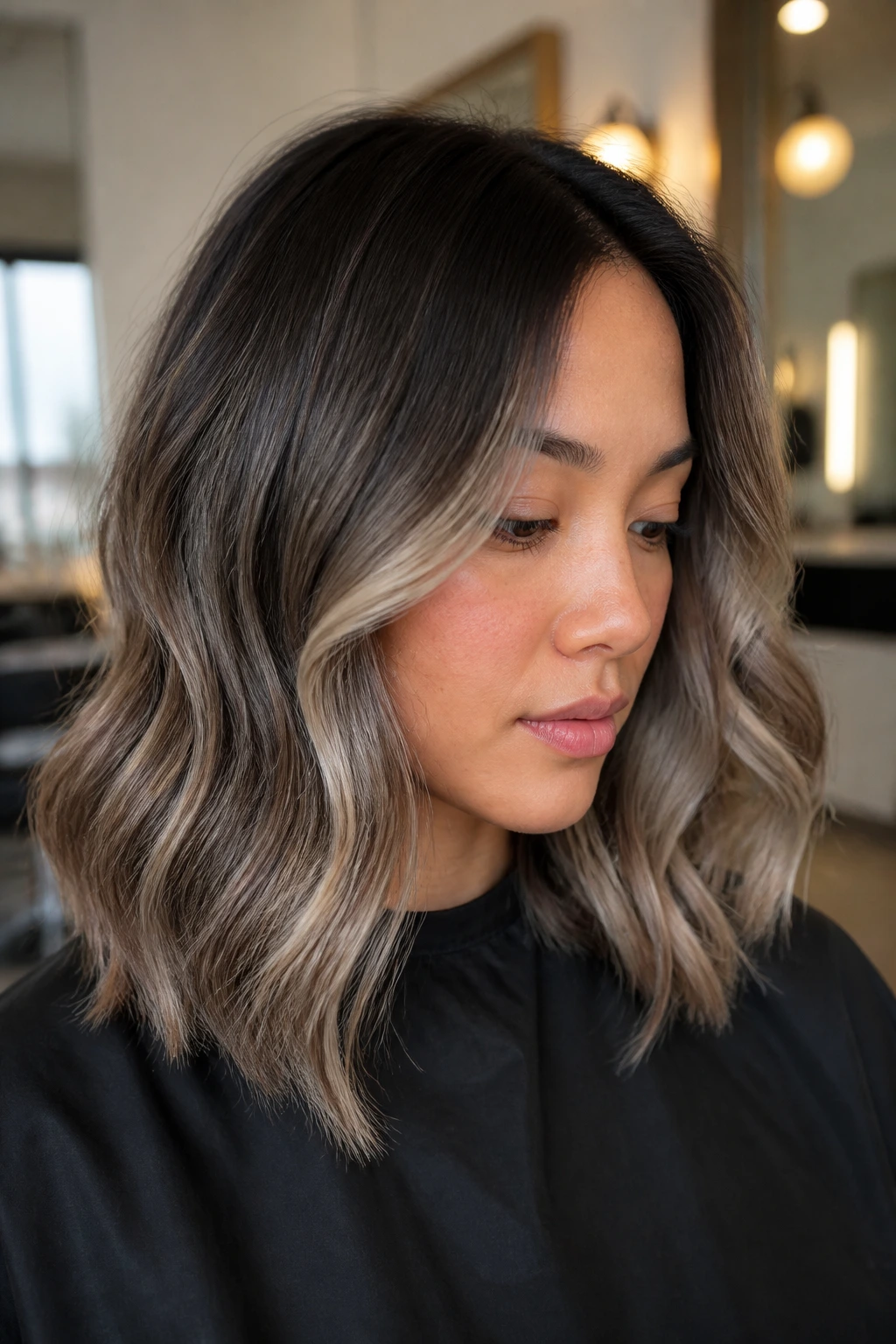 Portrait of a woman with smoky ash balayage ribbons in loose waves.