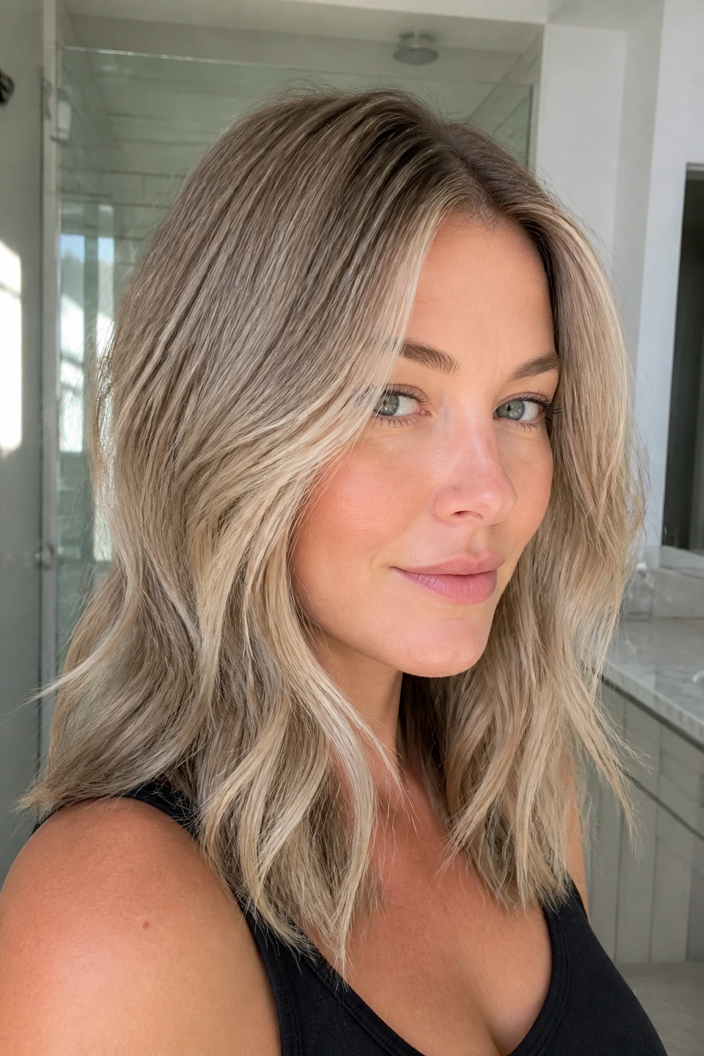 Close-up portrait of a real woman with ash blonde hair showing smooth roots and subtle texture