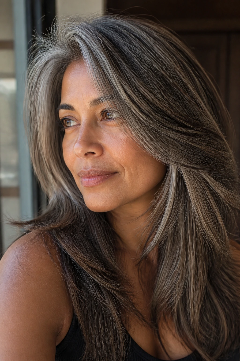 Close-up of thick hair with ash brown lowlights on tan skin.
