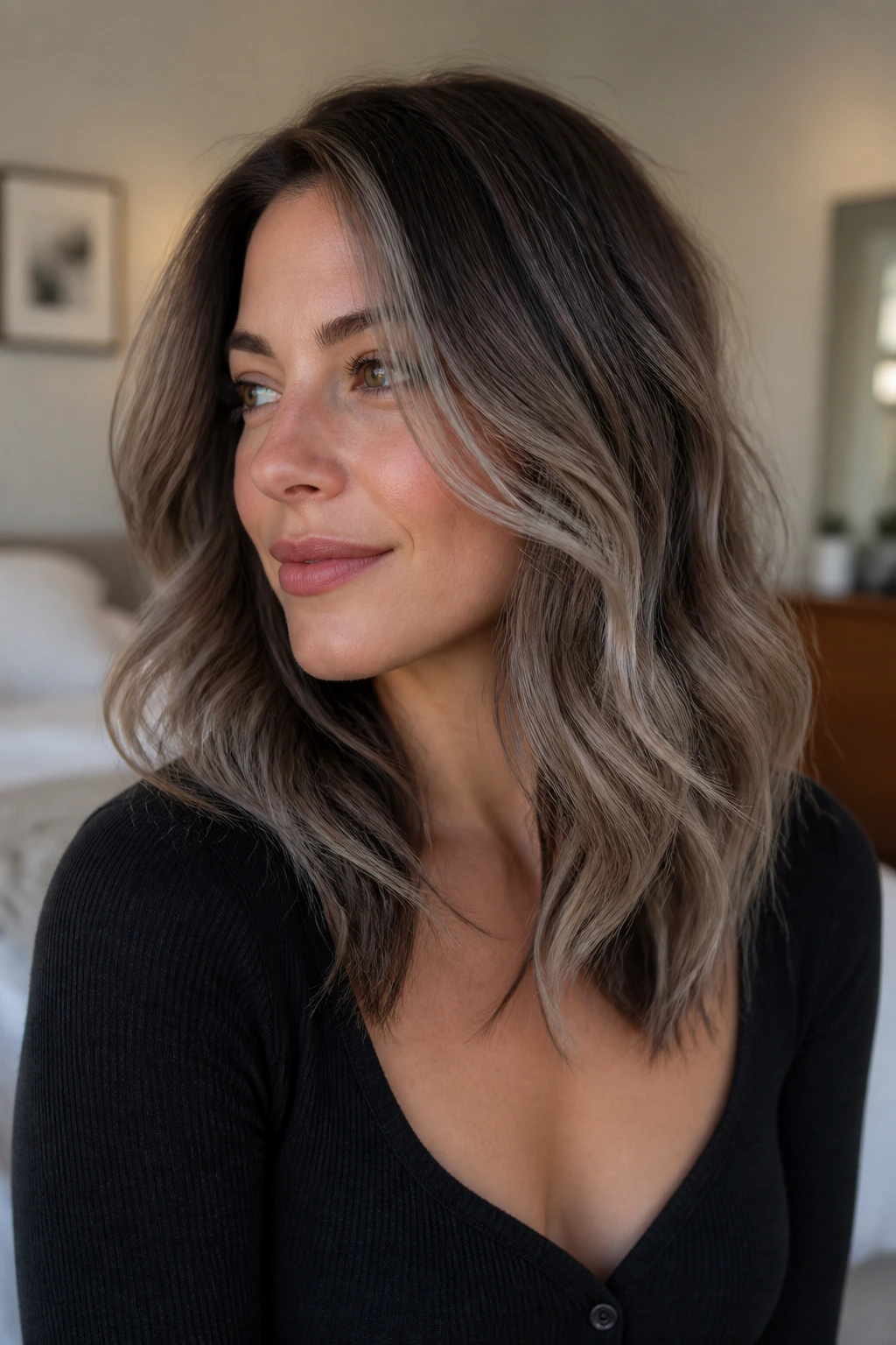 Close-up portrait of a woman with pearl-greige balayage on shoulder-length layered hair