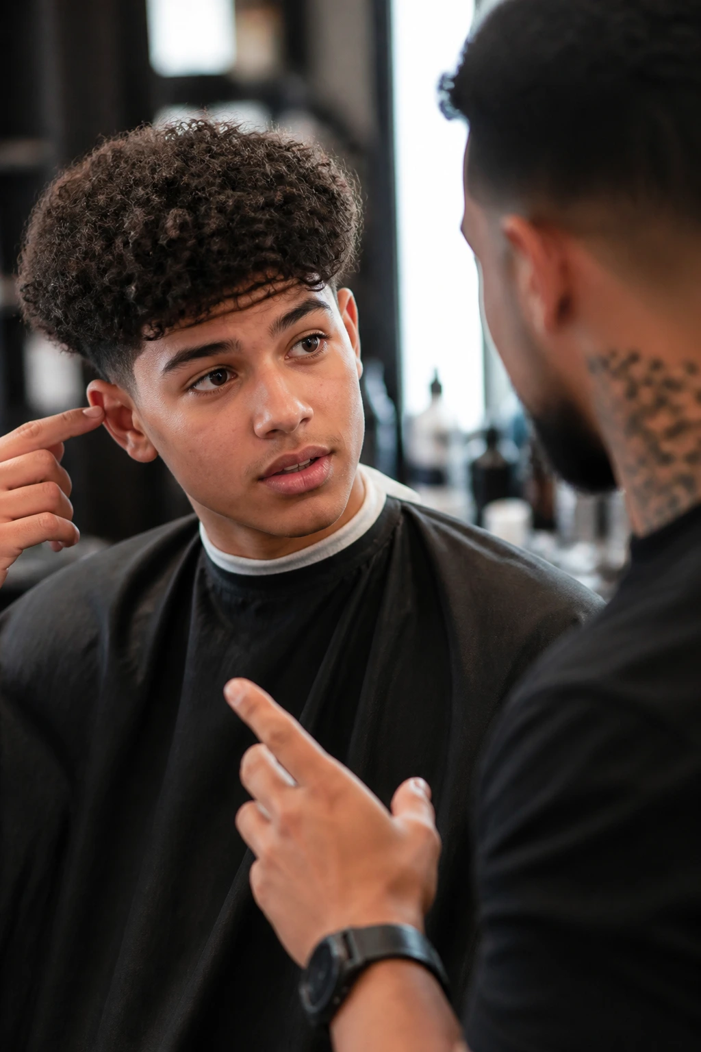 Boy in barber chair discussing taper with barber in a warm salon