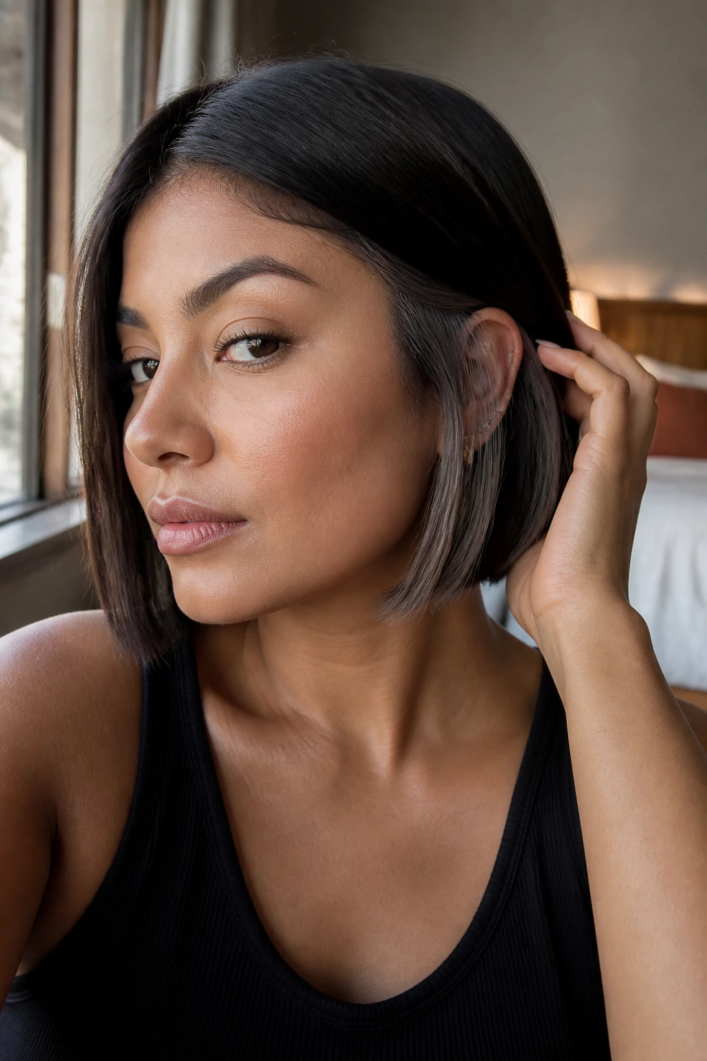 Close-up of a real woman with a blunt bob and smoky grey underlayers peeking from behind the ear.