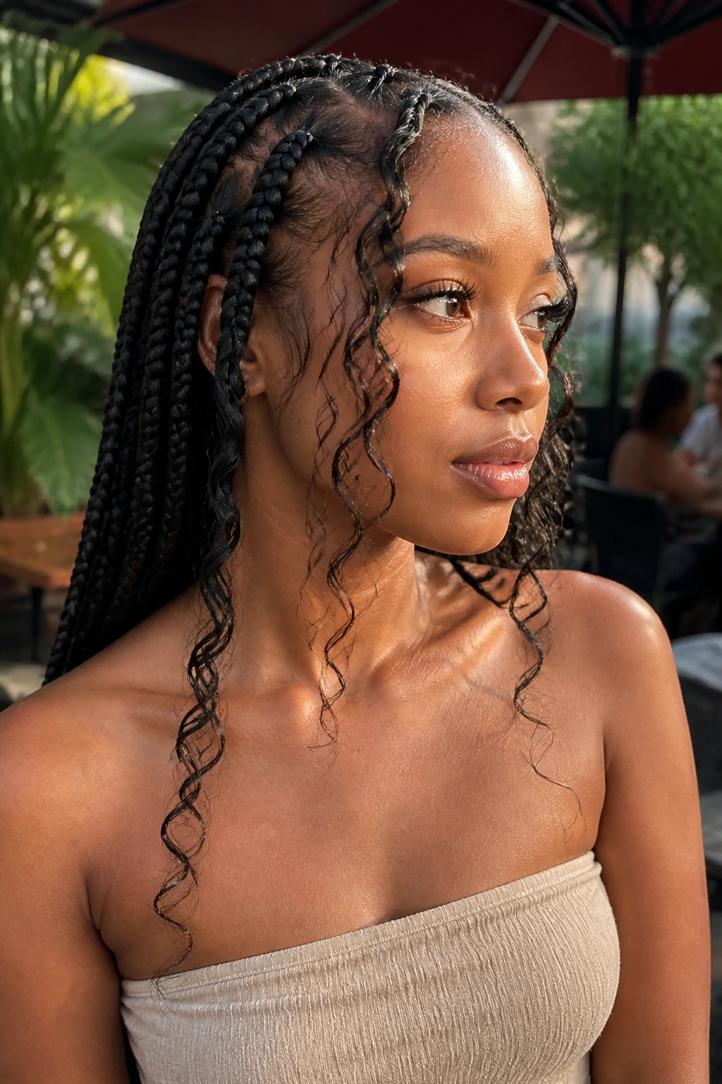 Close-up of a woman with curly face-framing strands among straight jumbo braids outdoors.