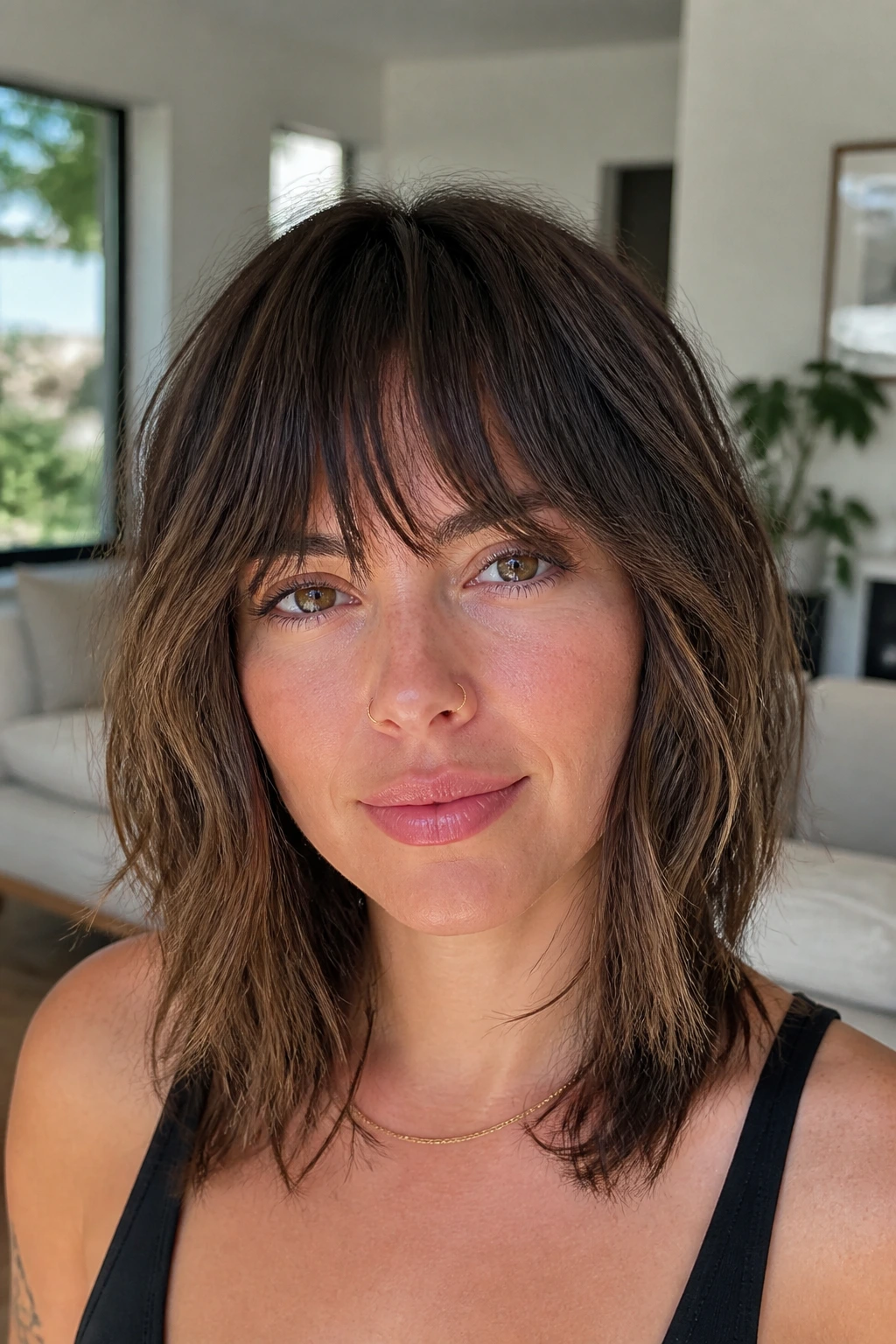 Close-up of real woman with brow-skimming shag fringe in daylight living room