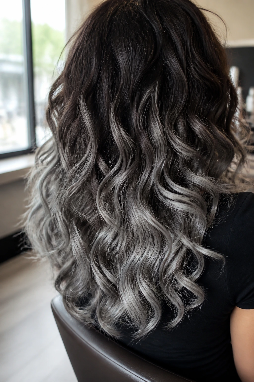 Back-of-head close-up of brunette curls with brushed aluminum ends in salon light