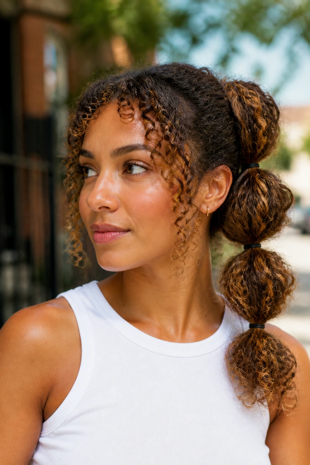Head-and-shoulders portrait of a real person with a bubble ponytail on shoulder-length curls and caramel highlights