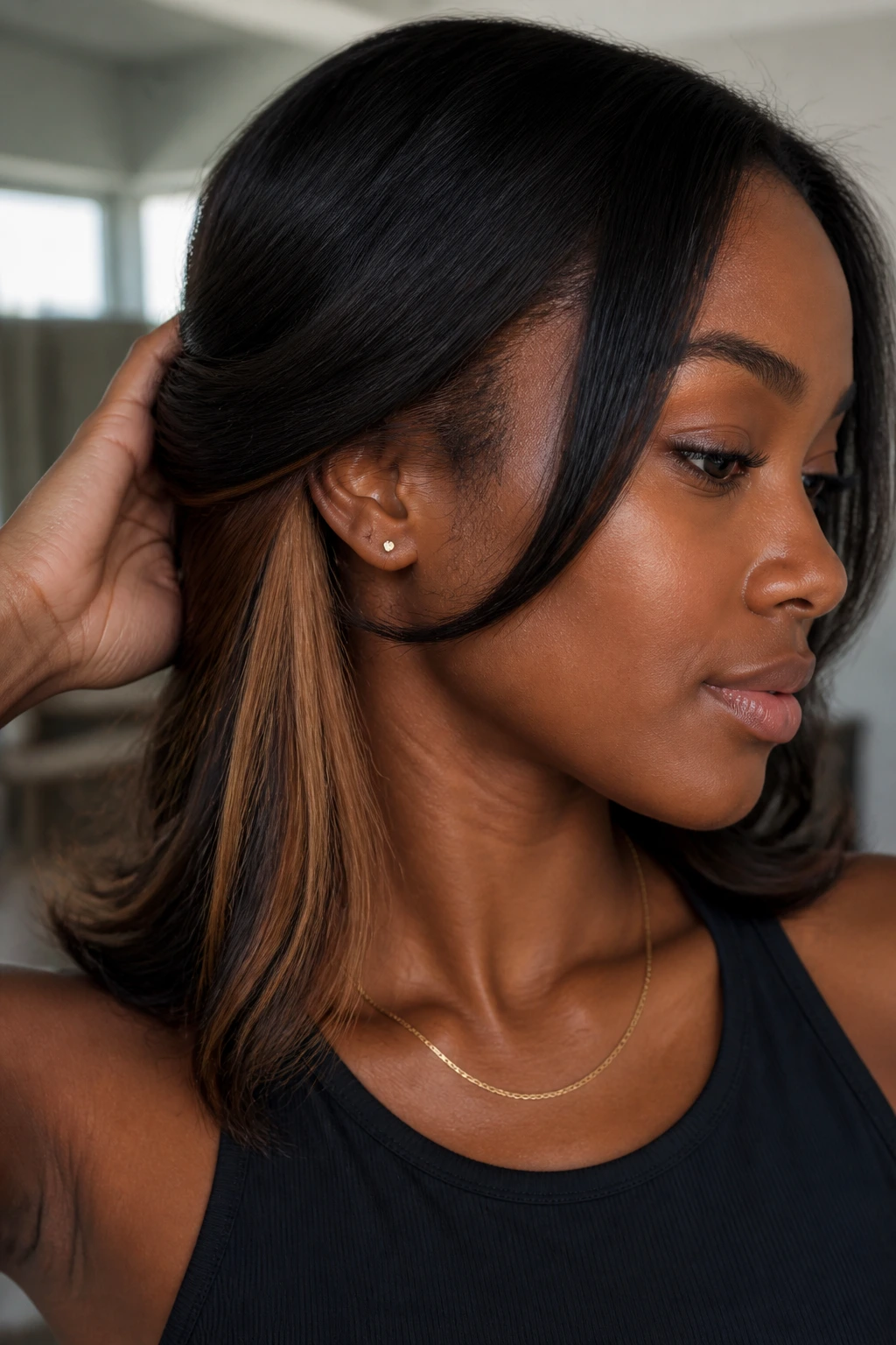 Close-up of a real woman with deep skin tone showing butterscotch peekaboo panels under the top hair layer.
