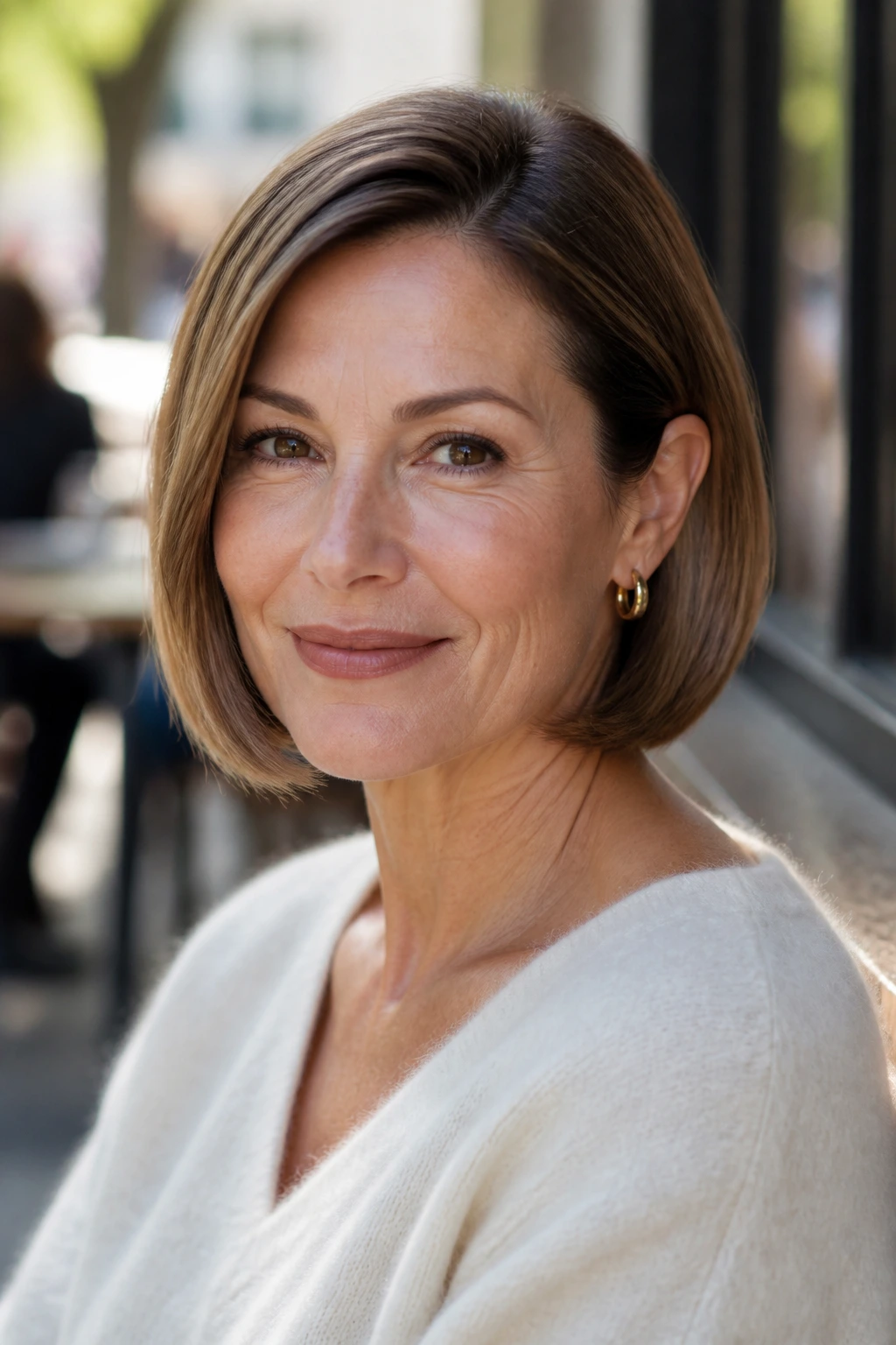 Close-up of a real woman with a soft C-curve bob tucked behind ear