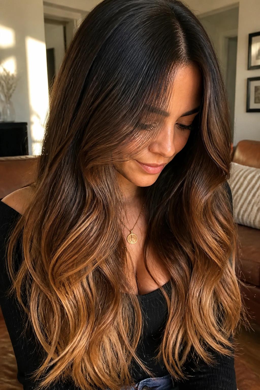 Real person with caramel-colored ends on long hair, warm lighting