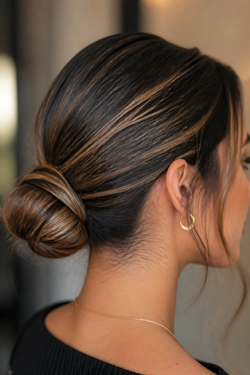 Sleek bun with warm caramel streaks visible around the face