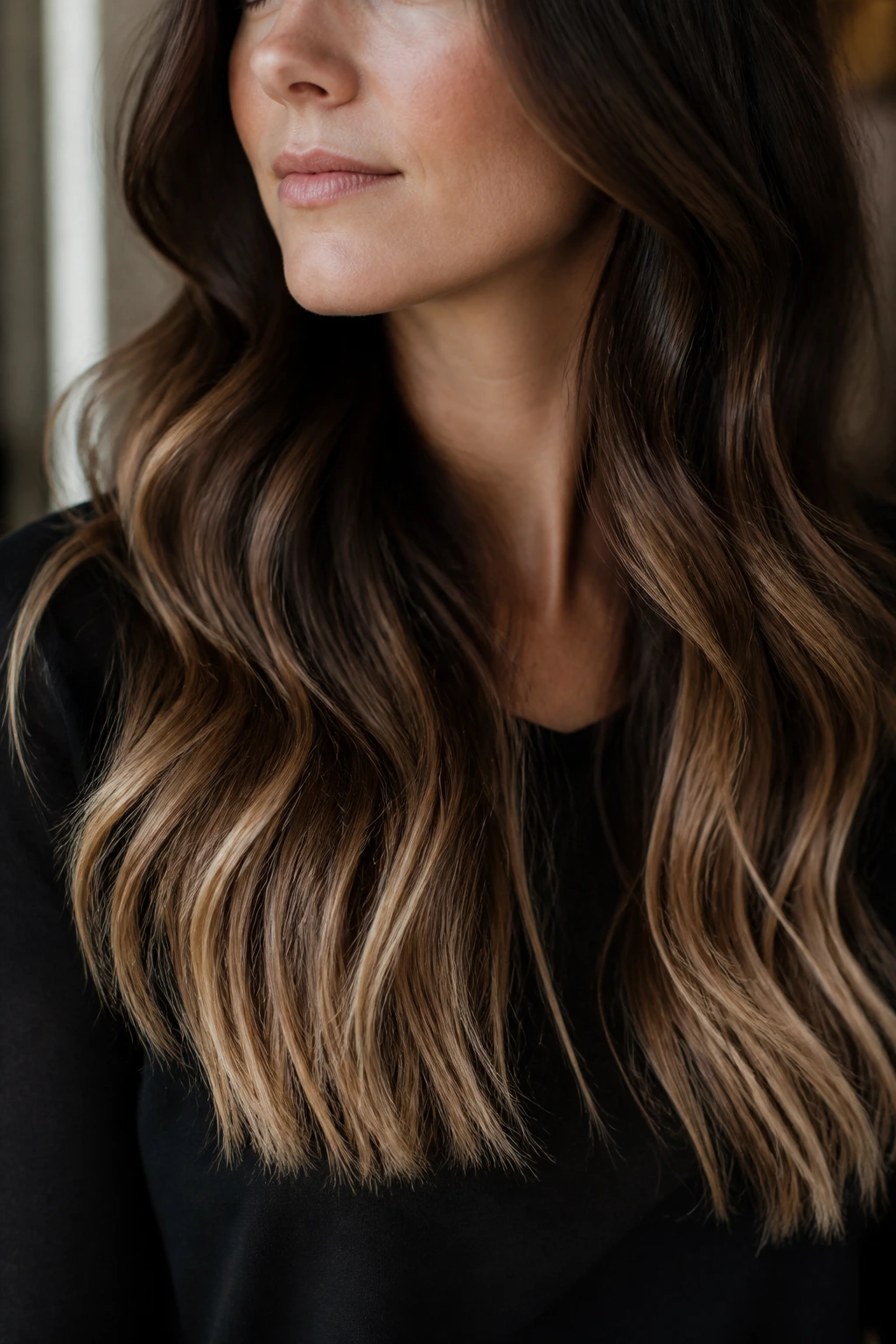 Close-up of a real woman highlighting champagne caramel ends on dark roast brunette hair