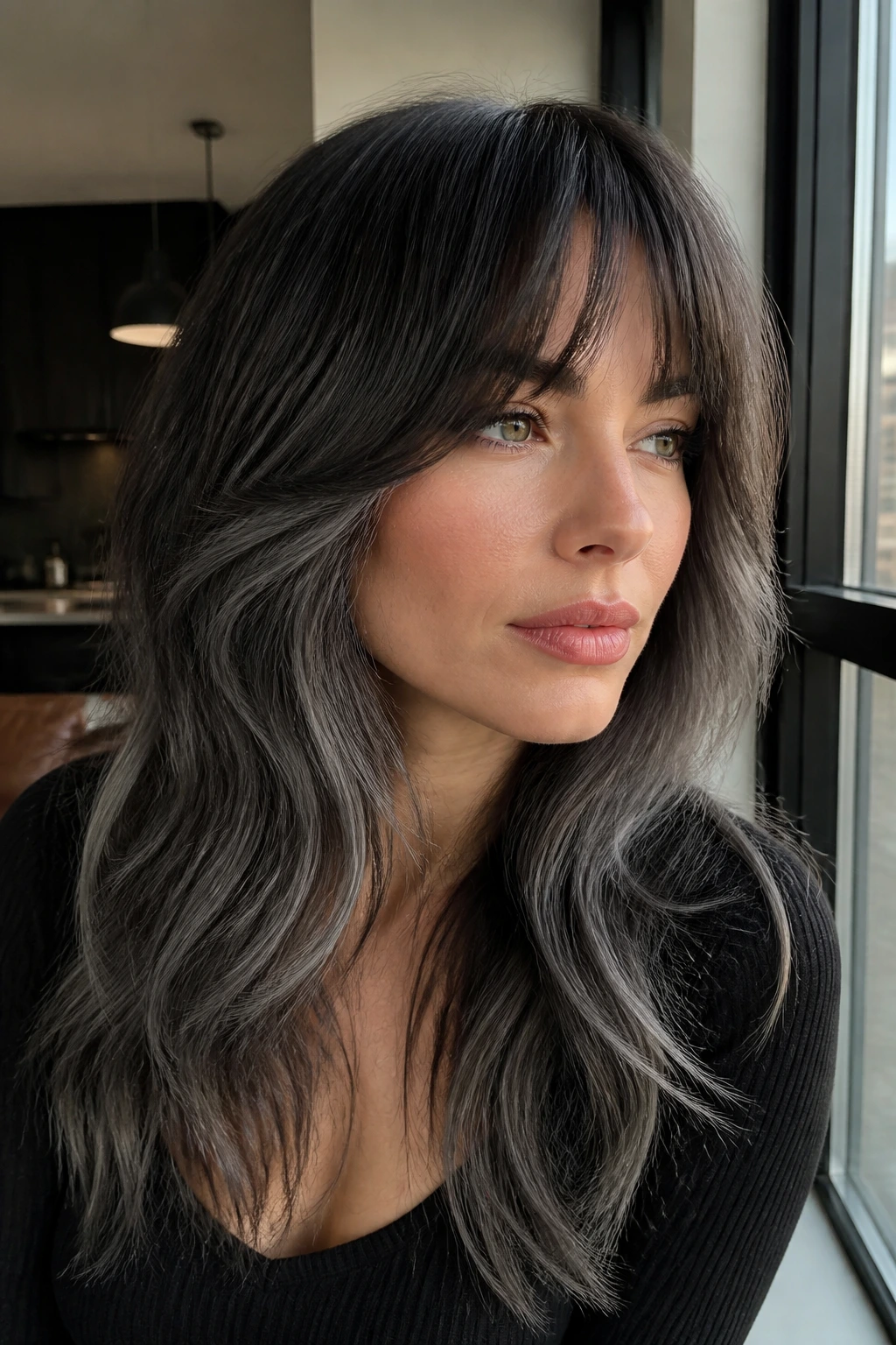 Close-up of a person with charcoal-to-slate balayage and long layered bangs