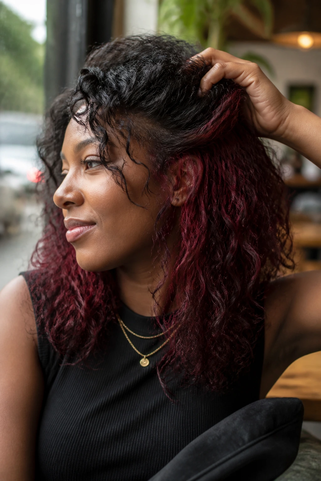 Close-up of a deep-skinned model with cherry cola peekaboo burgundy under-layer on curls