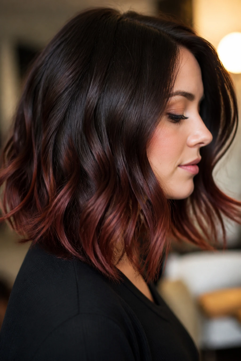 Side portrait of a real woman showing chocolate brown hair with cherry ends in warm indoor light