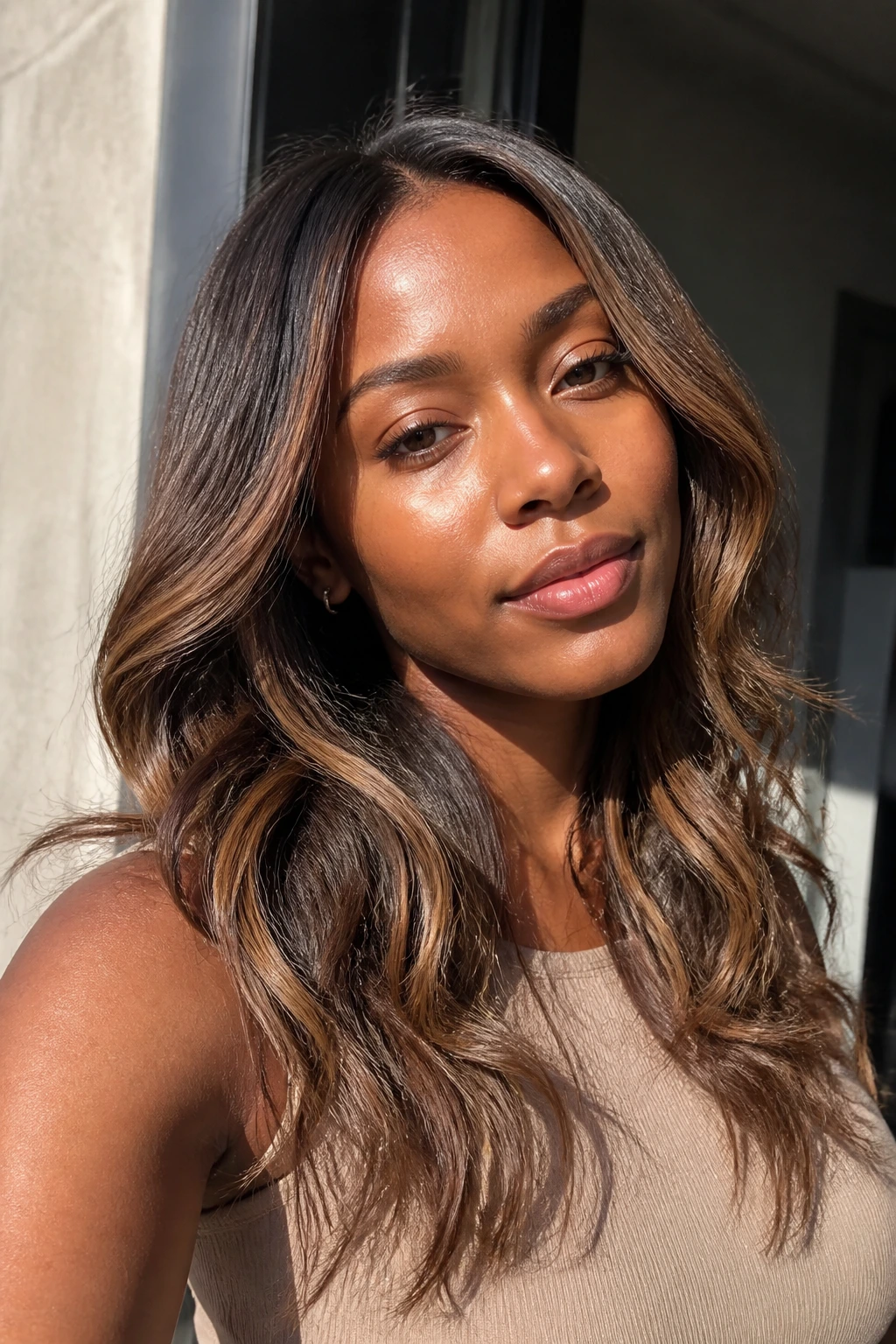 Close-up portrait of a real woman with sunkissed coffee balayage in natural light.