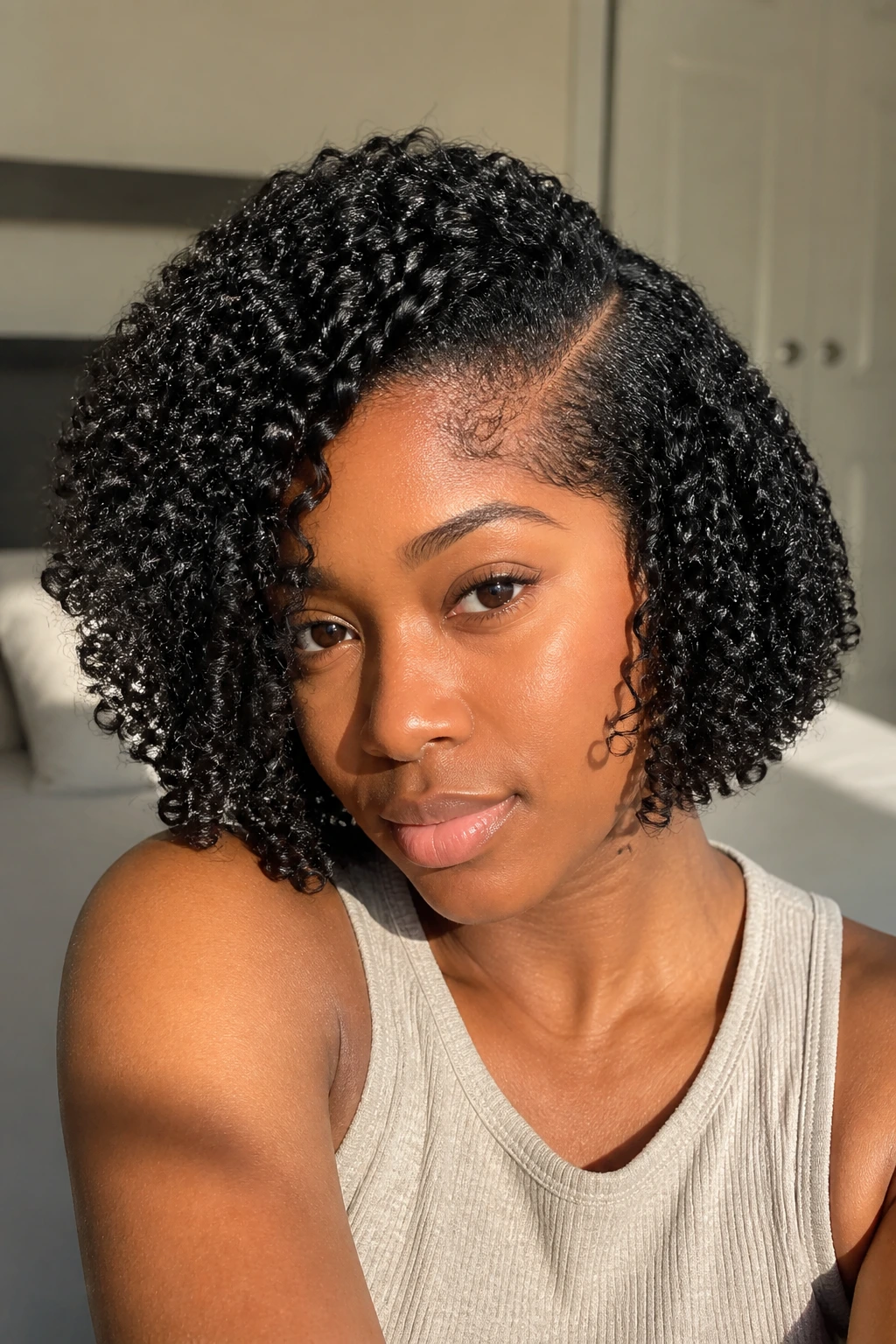 Close-up portrait of a real woman with a deep side-part coil bob showing diagonal cheek-line