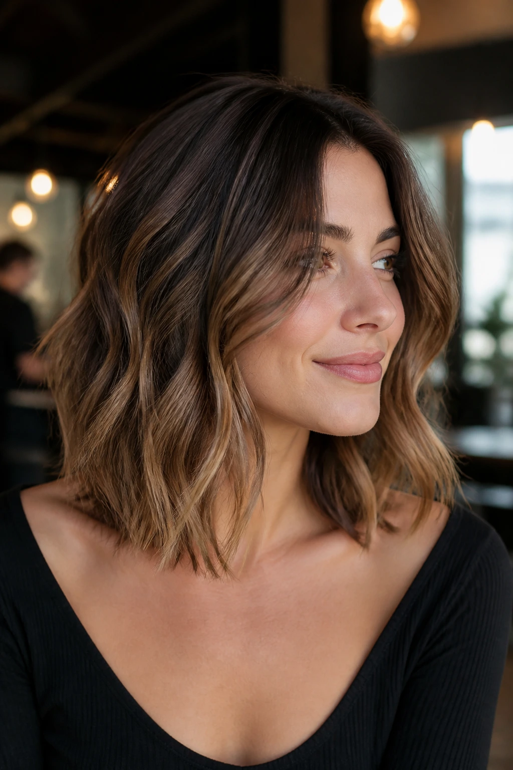 Close-up of a real person with collarbone-length hair and scattered caramel highlights