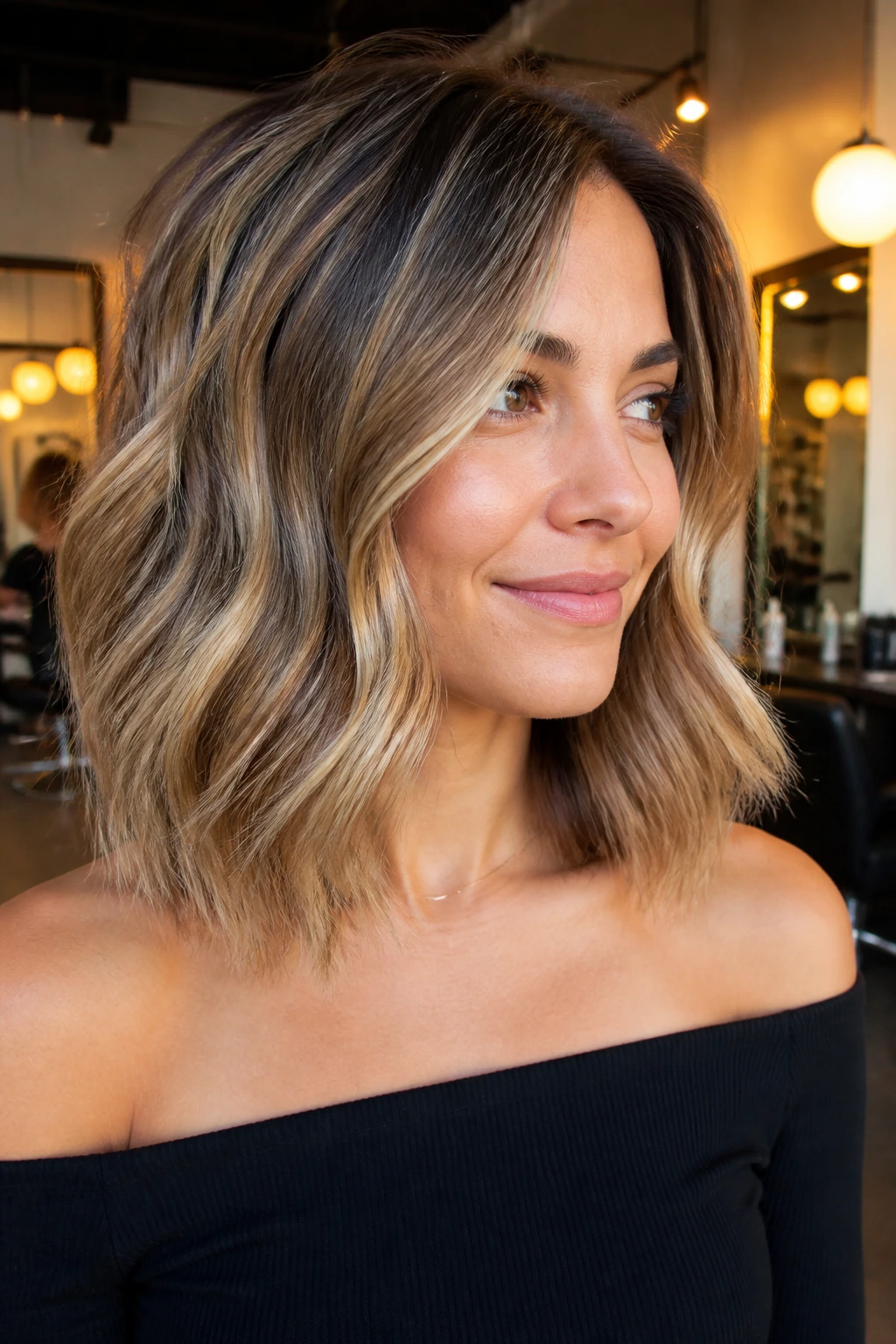 Close-up of a real woman with a collarbone-length lob and loose waves in a warm salon