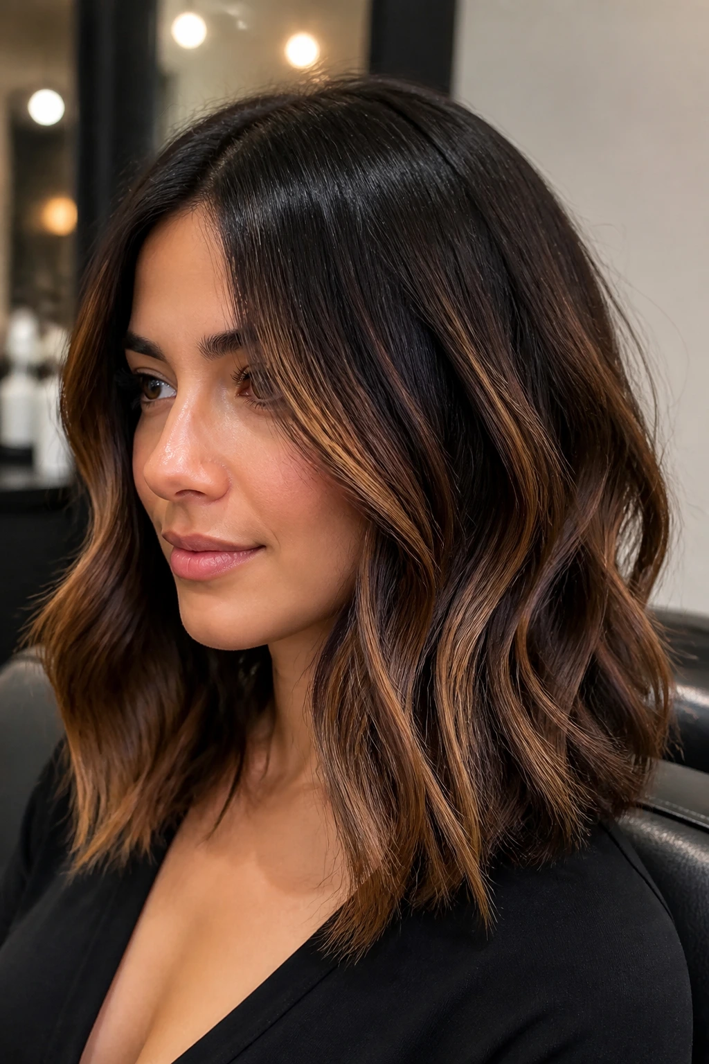 Close-up of a real woman’s hair showing beige-caramel color boosters in dark hair