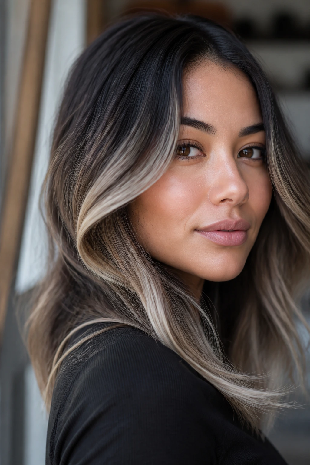 Close-up portrait of a real person with dark hair and cool blonde placement at the cheeks with a shadow root