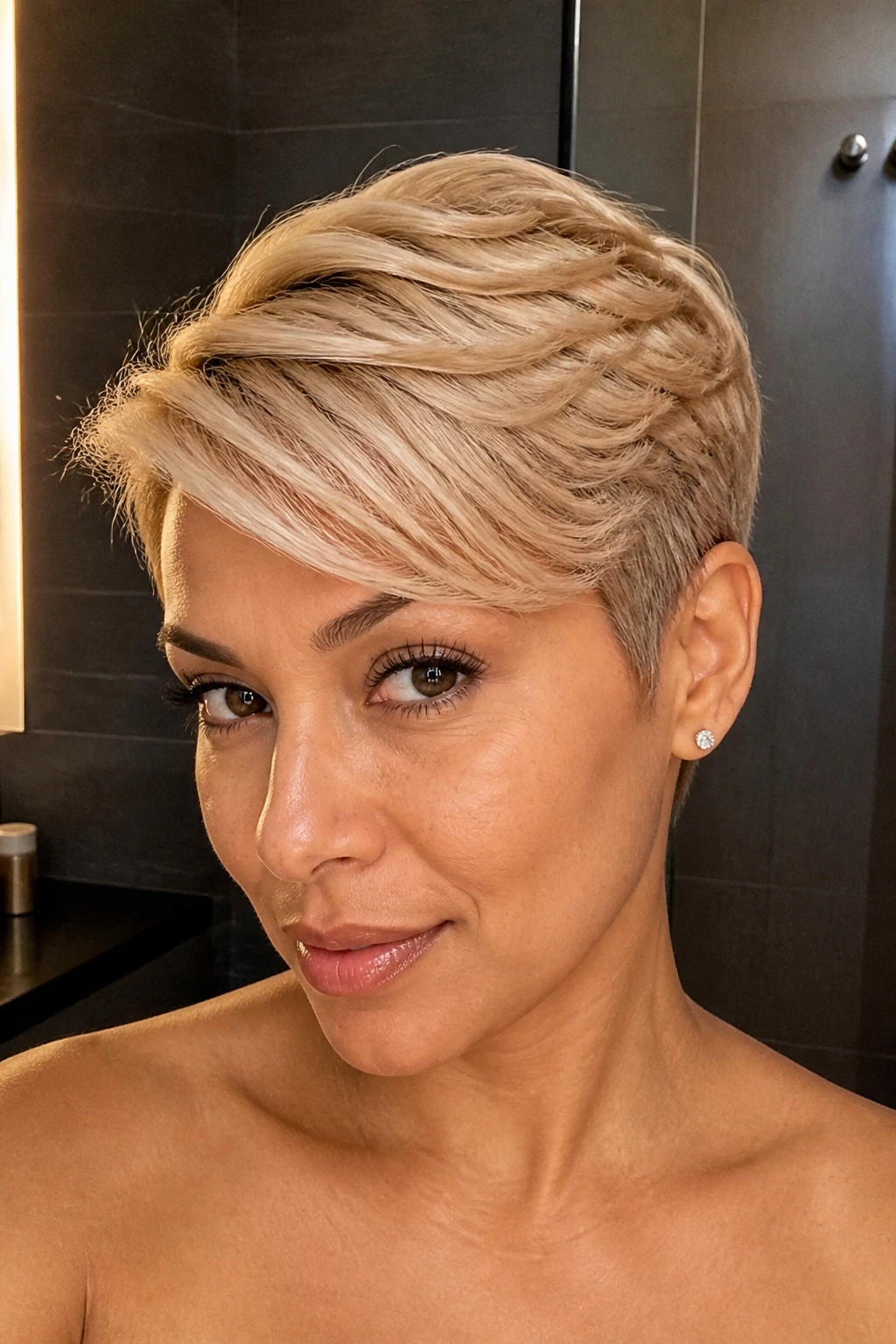 Close-up of a real woman with cream blonde pixie and side sweep in stylish lighting.
