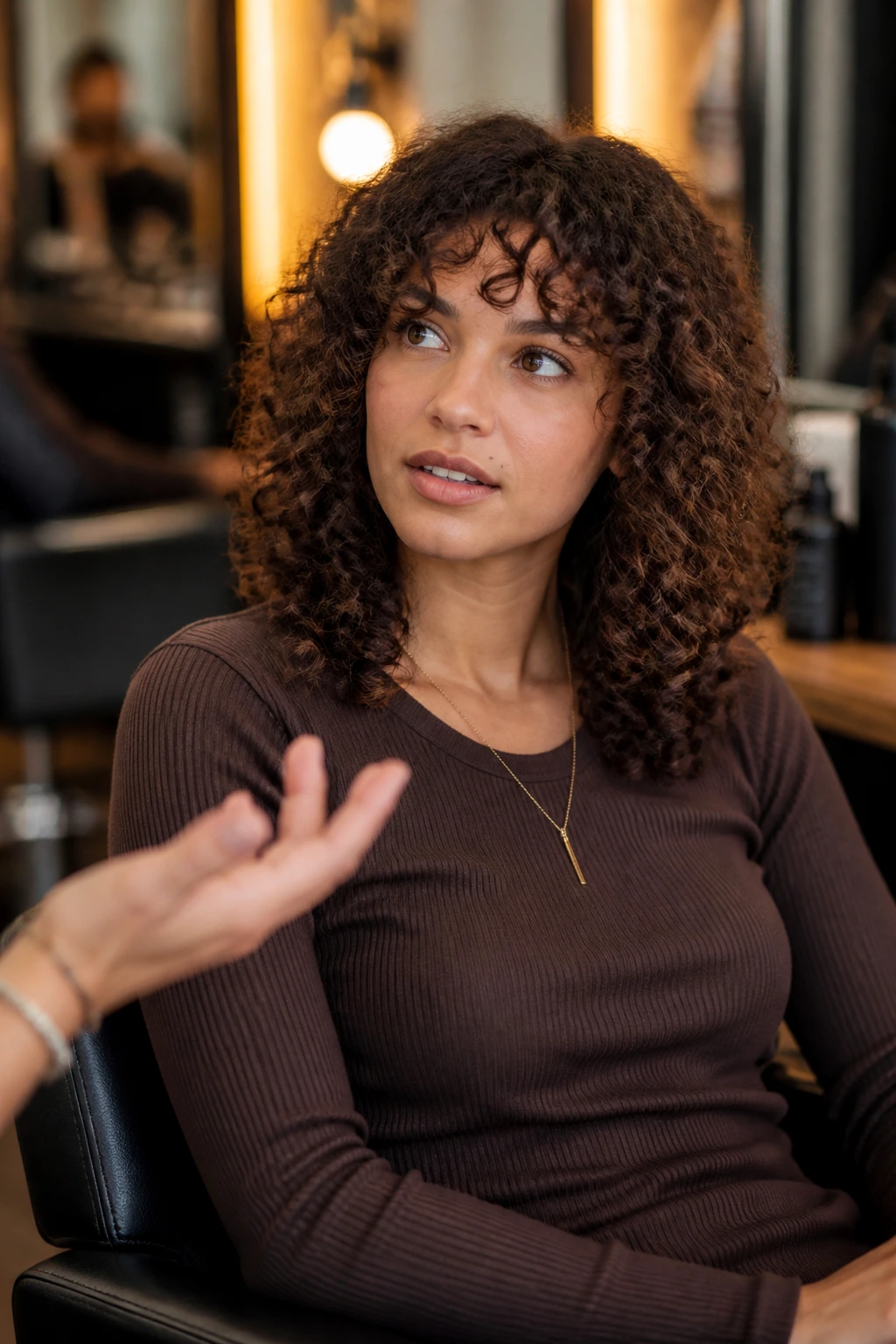Portrait of a person in a salon chair discussing curl-by-curl cut with a stylist.