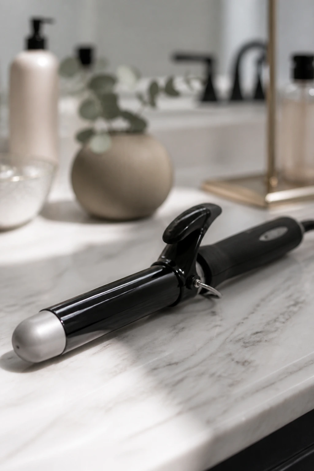 Close-up of a curling iron on a clean bathroom counter