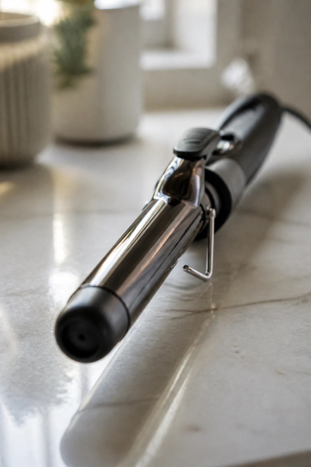 Close-up of a curling iron on a clean counter with soft lighting