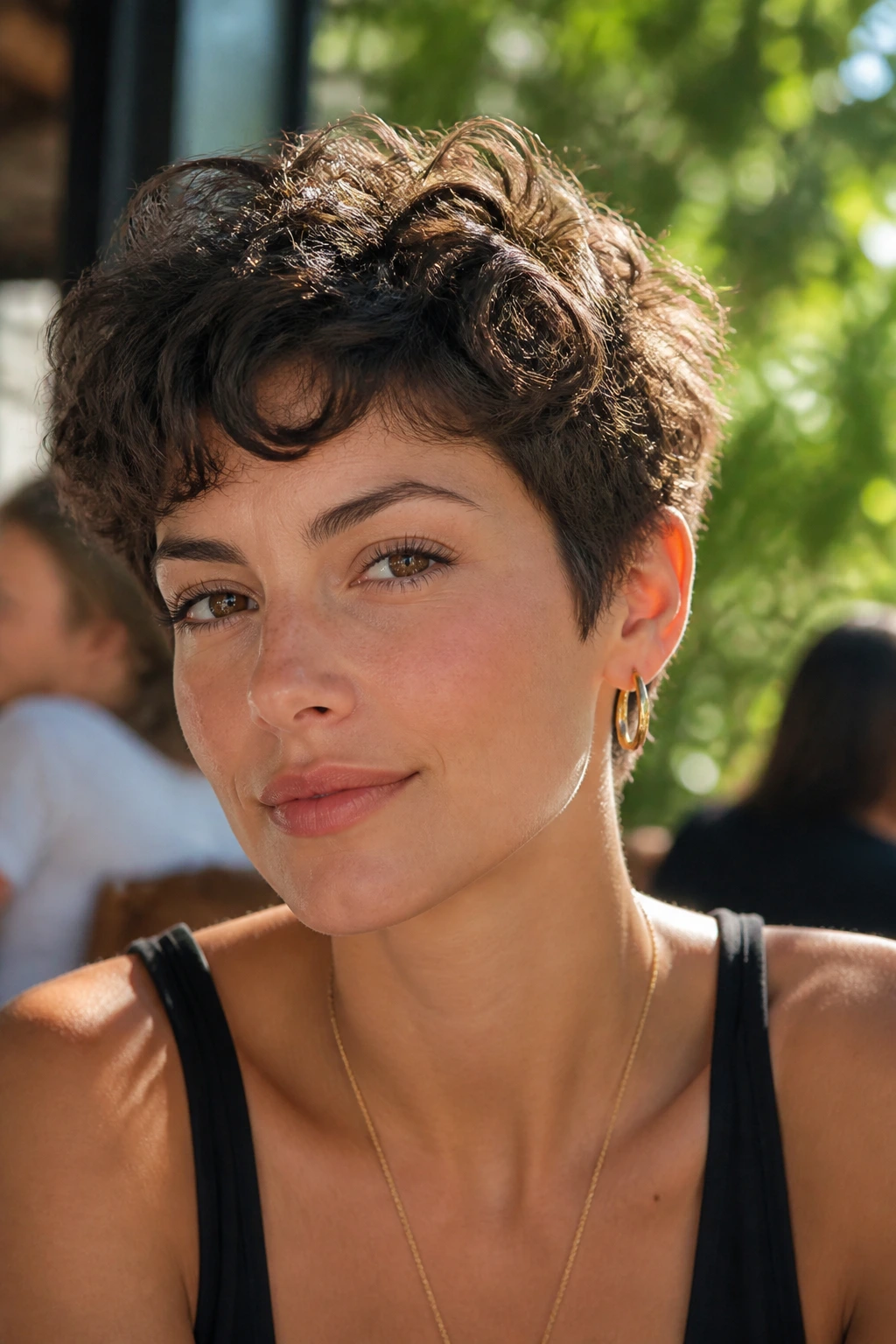 Close-up of a woman with curly bixie haircut in outdoor cafe setting