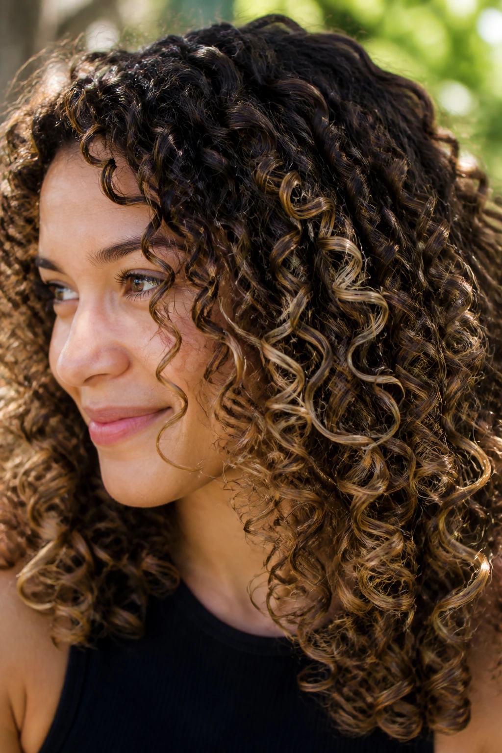 Close-up of curly hair with beige highlight pops along ringlets
