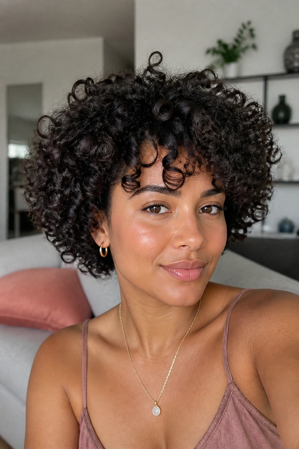 Close-up portrait of a real woman with a shrinkage-friendly curly haircut in a cozy room