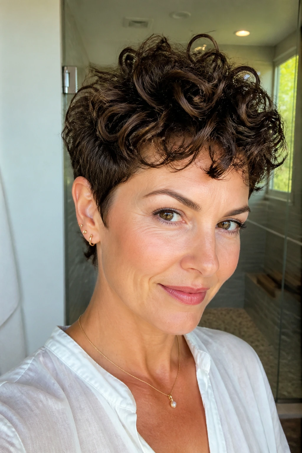 Portrait of a real woman with a curly pixie haircut featuring longer curls on top.