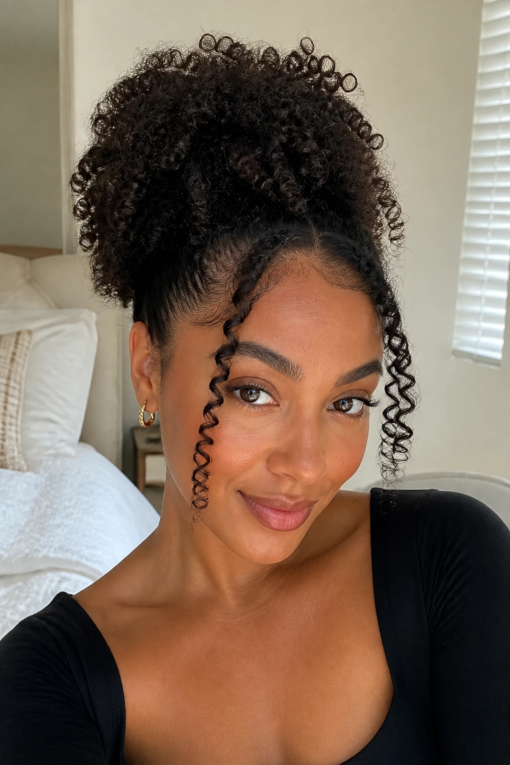 Close-up of real person with curly puff and tendrils curling away from face in bright room