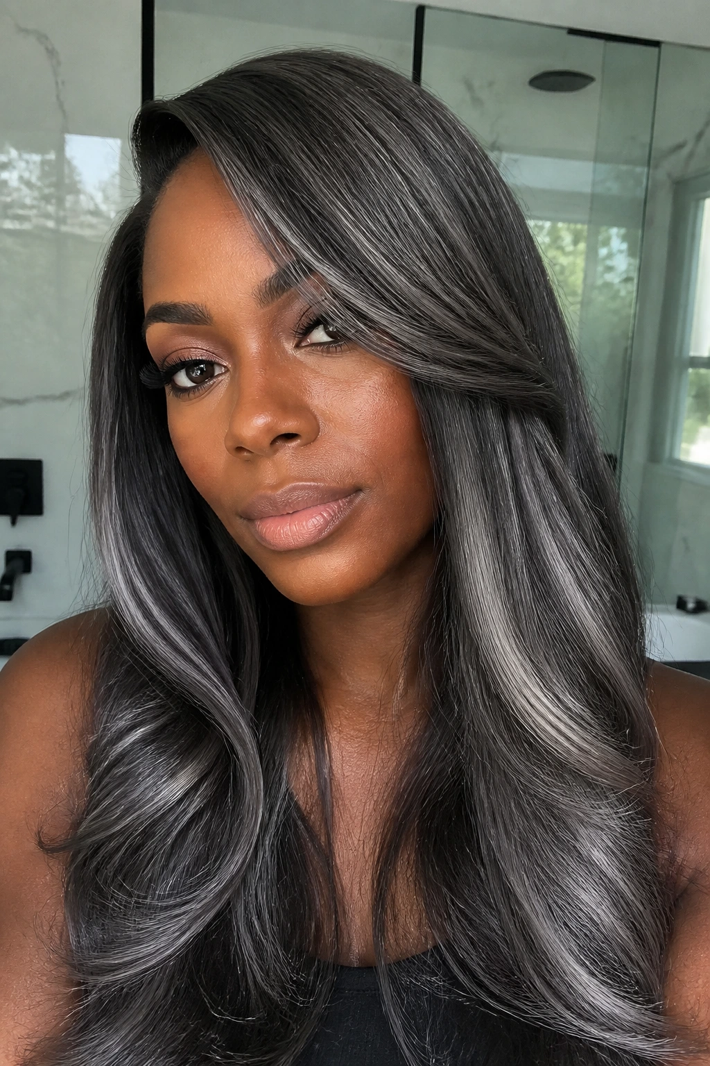 Close-up of a real person with dark-chrome lengths featuring chrome panels through hair on deep skin.