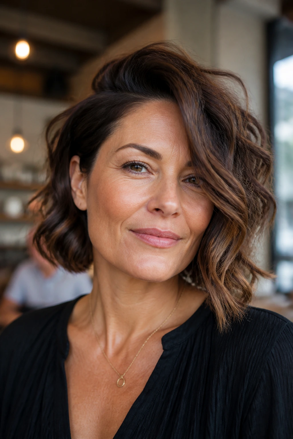 Portrait of a woman with deep side-part and asymmetrical bob in warm indoor light