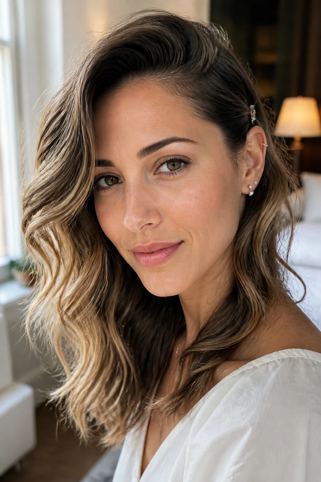 Close-up of an oval-faced woman with a deep side part and tucked-behind-ear waves.