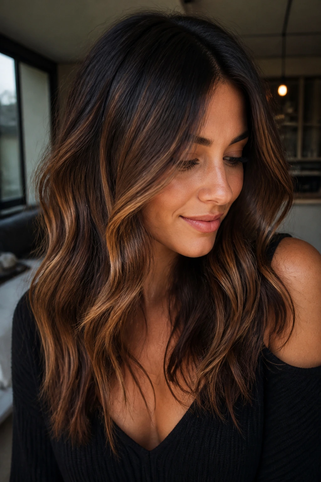 Brunette with deep roots and warm gold-brown highlights in soft window light.
