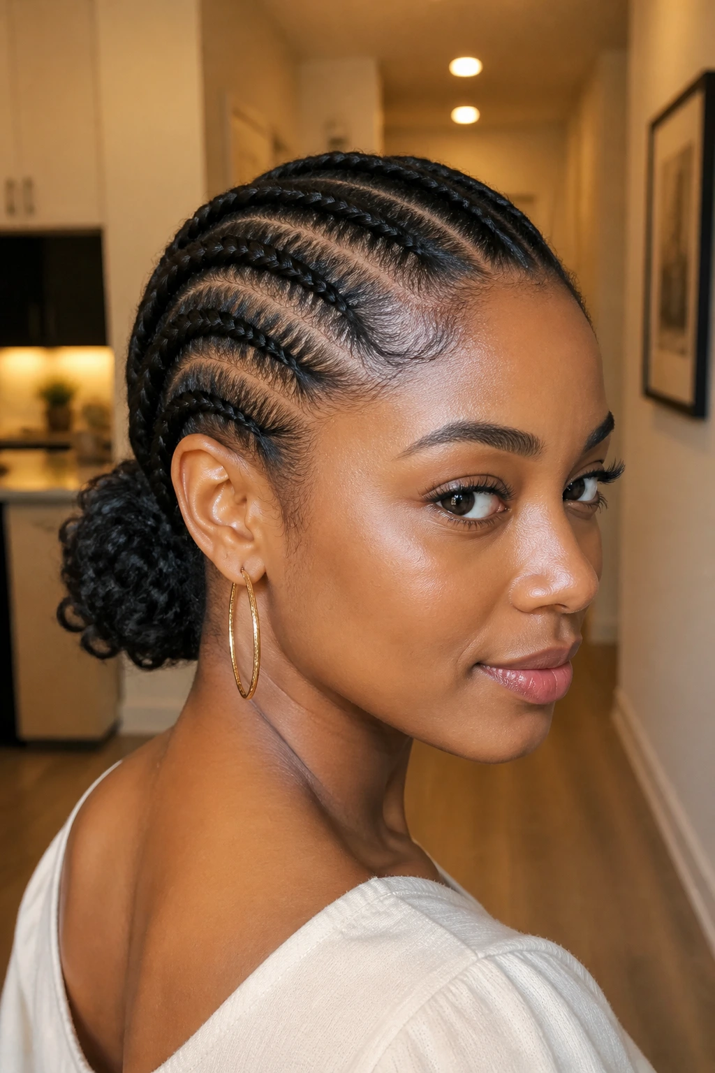 Close-up of diagonal cornrows flowing into a low curly bun on a real person