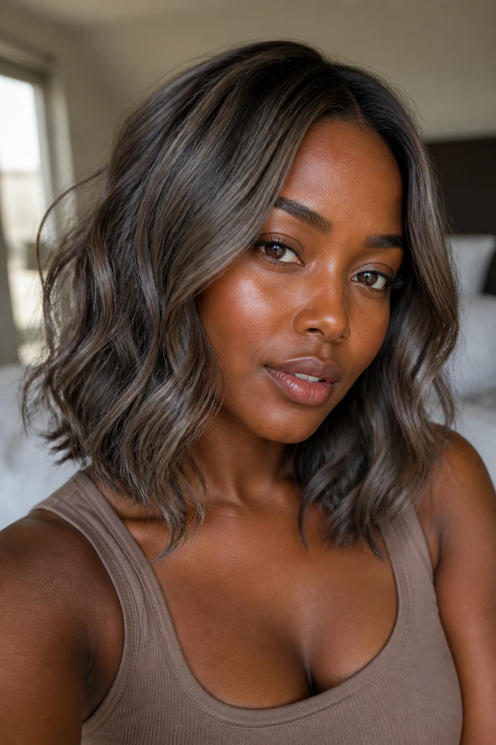 Close-up of a real person with driftwood brown wavy hair on deep skin tone in soft natural light