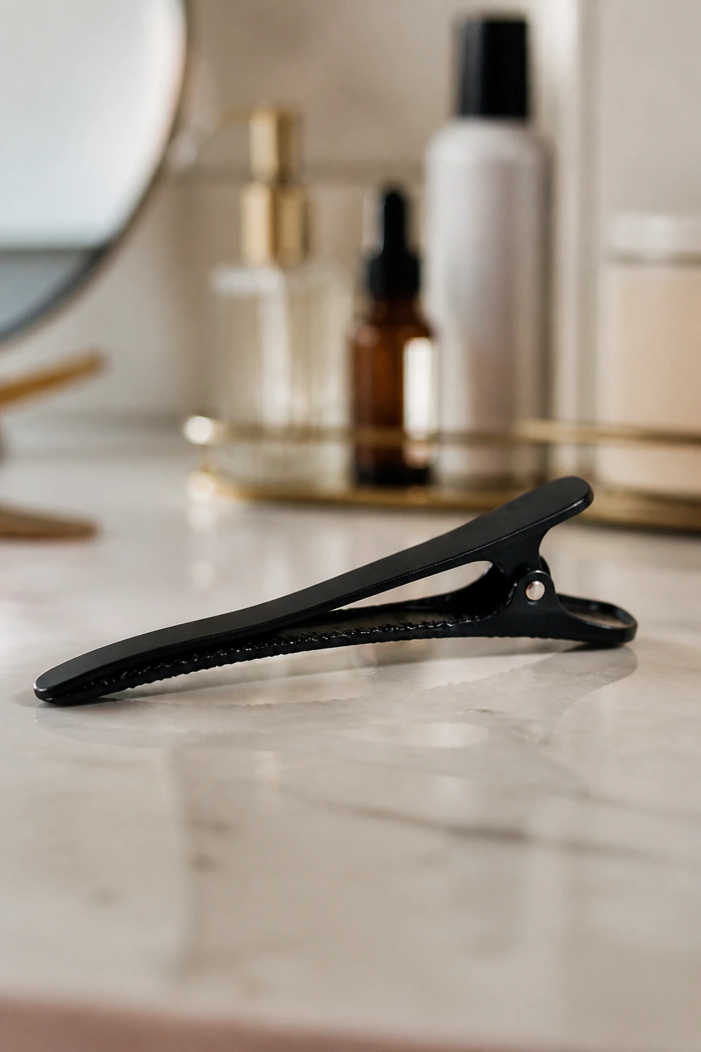 Close-up of a duckbill clip on a clean surface with blurred vanity items