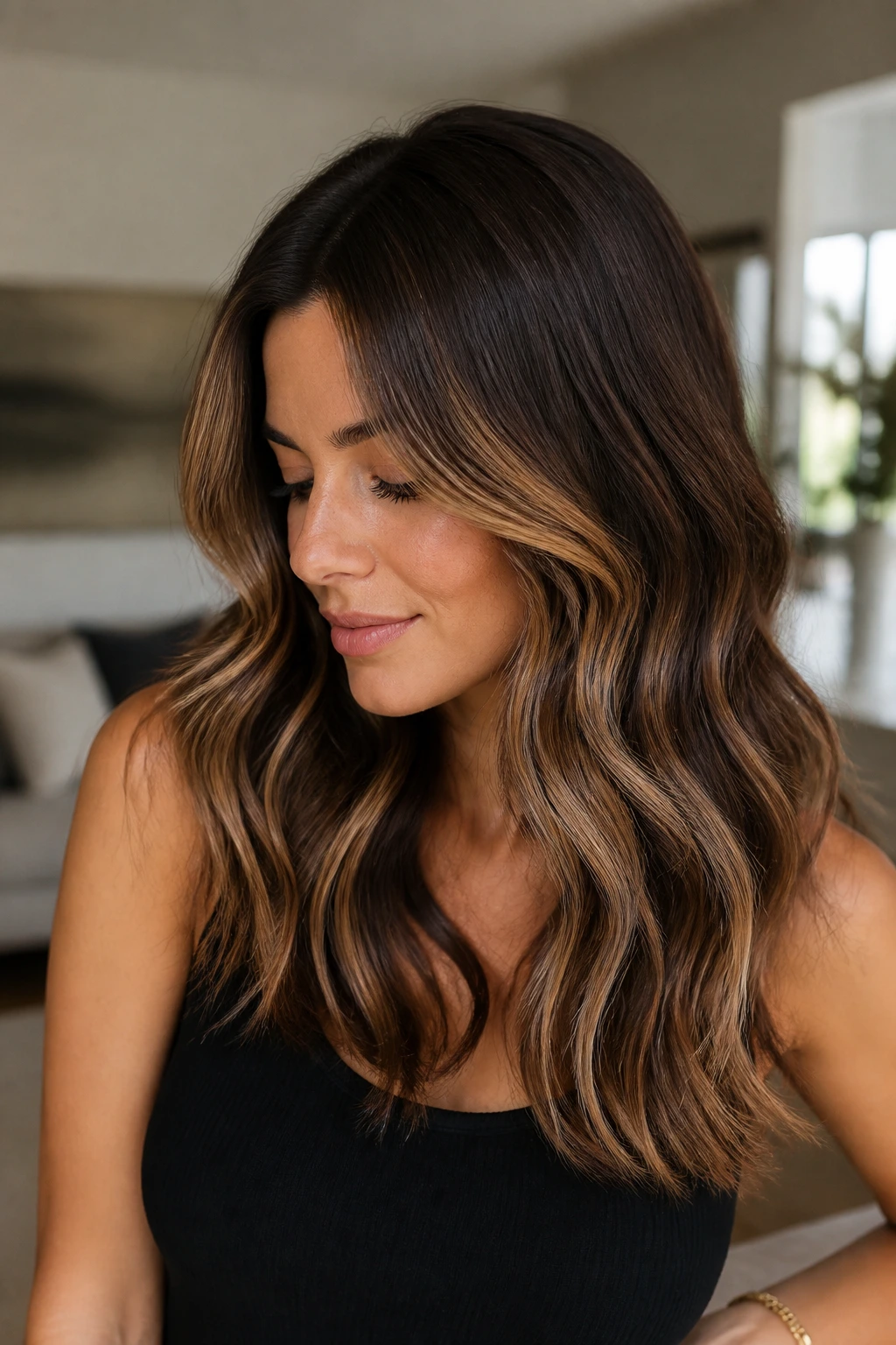 Close-up portrait of a real woman with espresso base hair and caramel ribbons through mid-lengths.