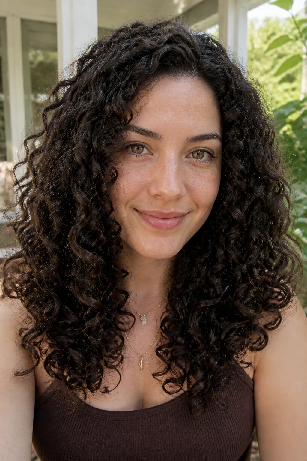 Close-up portrait of a woman with glossy espresso coils in natural daylight