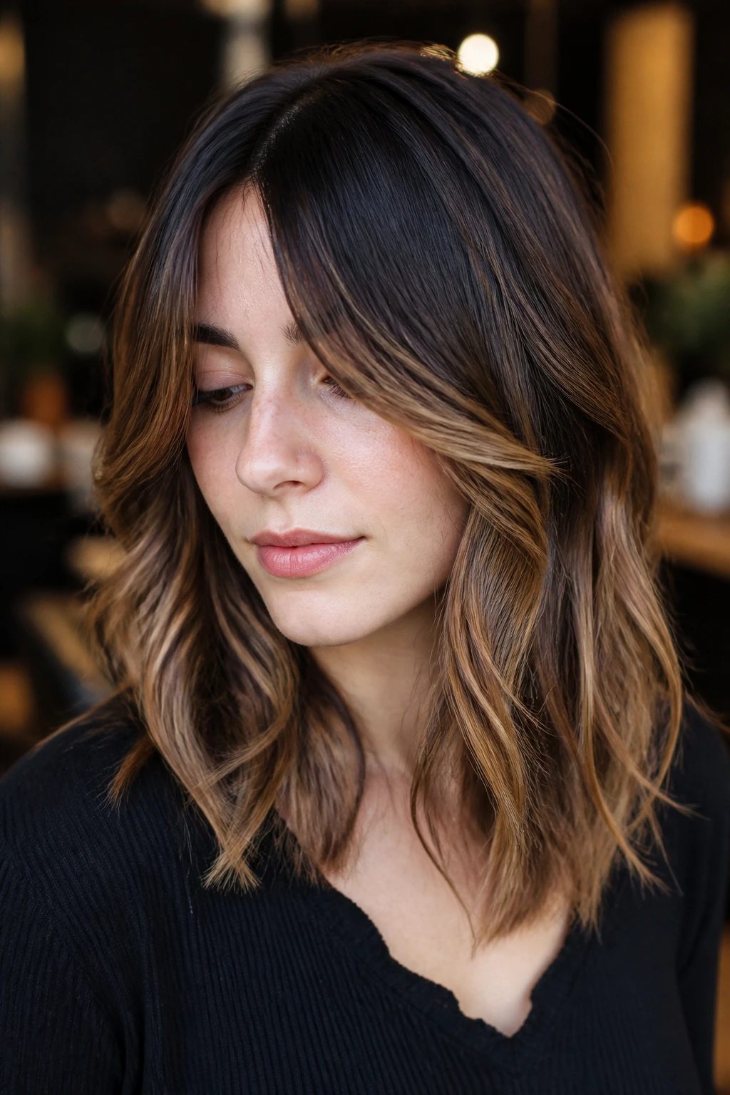 Real woman with espresso roots and mid-length caramel highlights