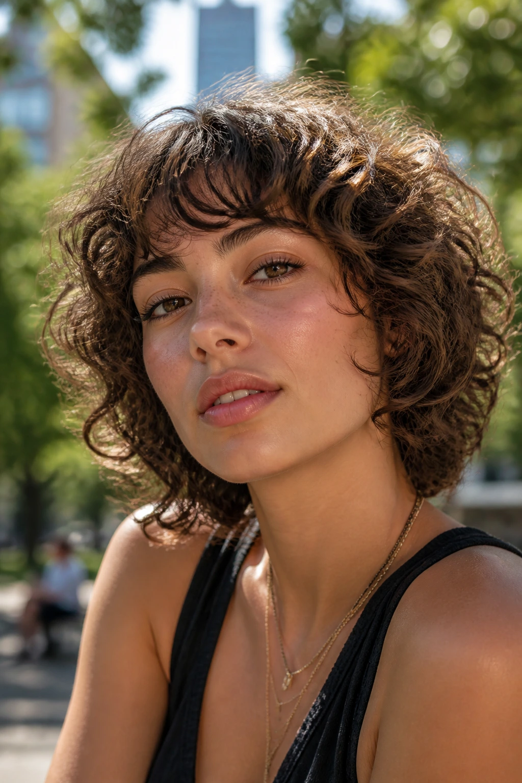Portrait of a real woman with feathered mushroom cut on thick curls in a park setting.