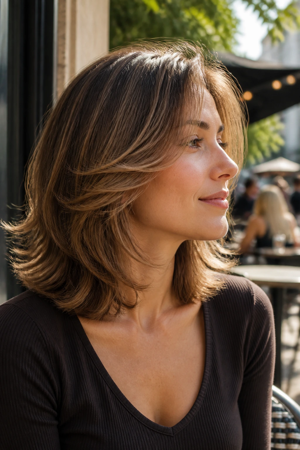 Profile portrait of a real woman with feathered shoulder-length layers flicking away from the face.