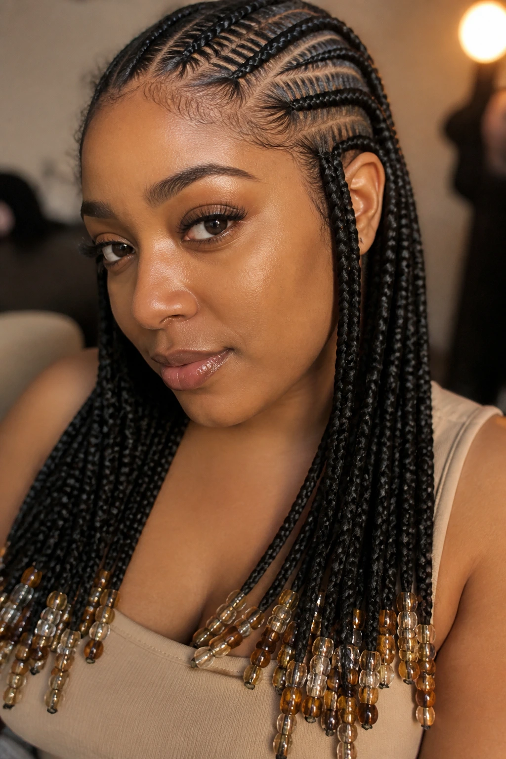 Close-up portrait of a real woman with feed-in braids and beaded ends in warm indoor light