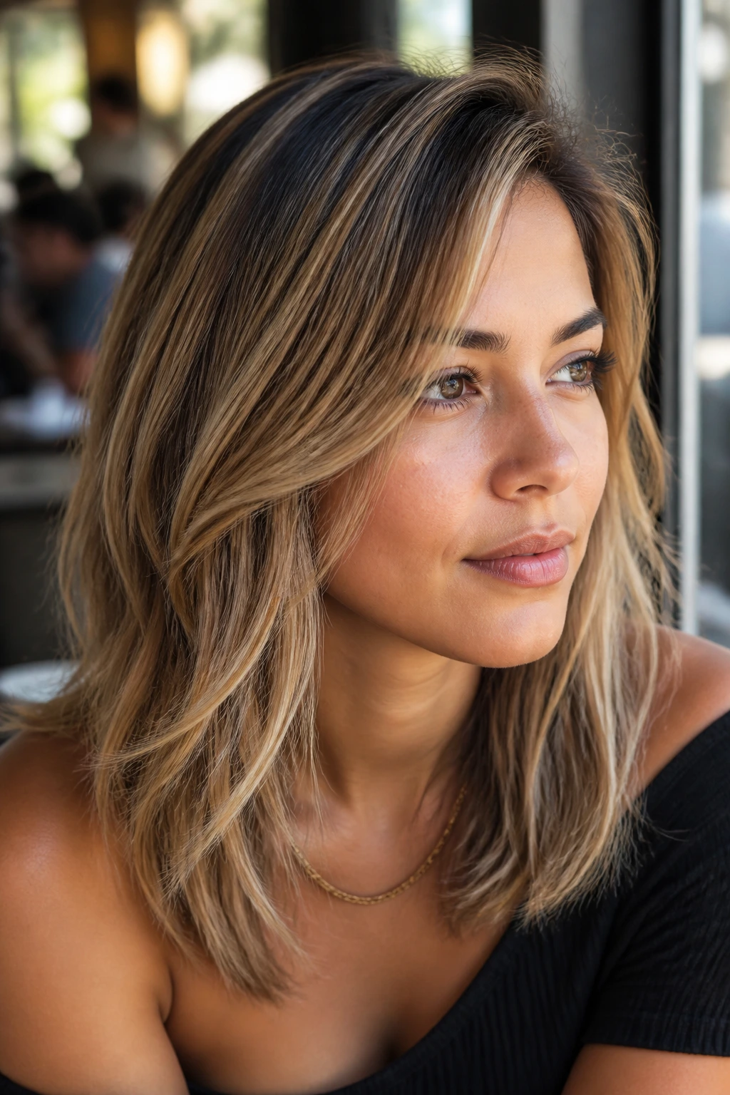 Close-up portrait of a real woman with golden sand balayage over fine layers
